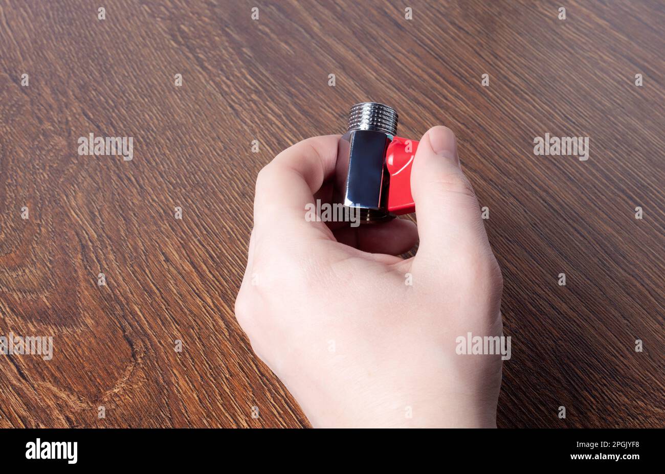 Water ball faucet with red valve in male hand. Brass water tap close up