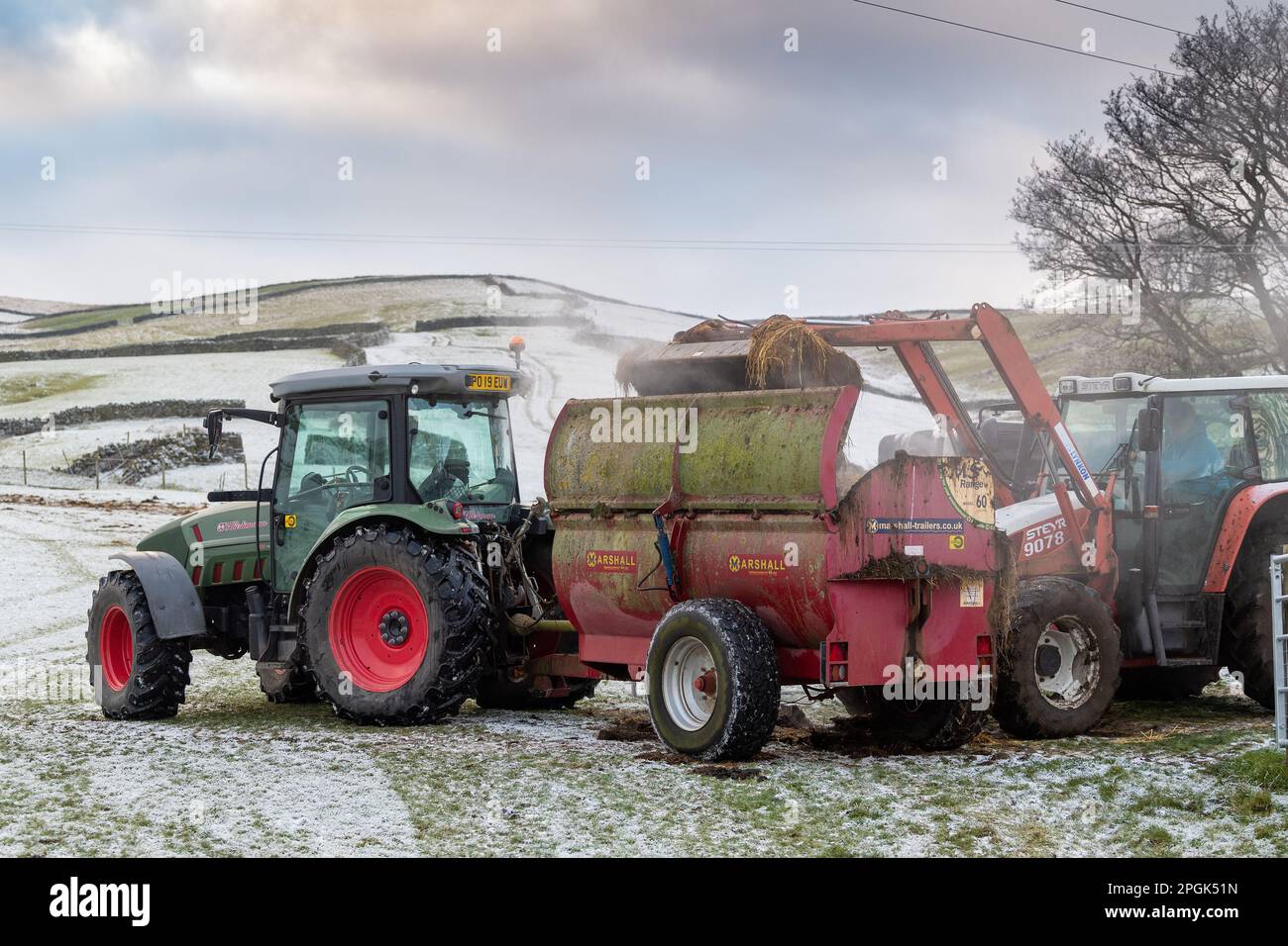 Filling a rotary muckspreader with farm yard manure to spread on