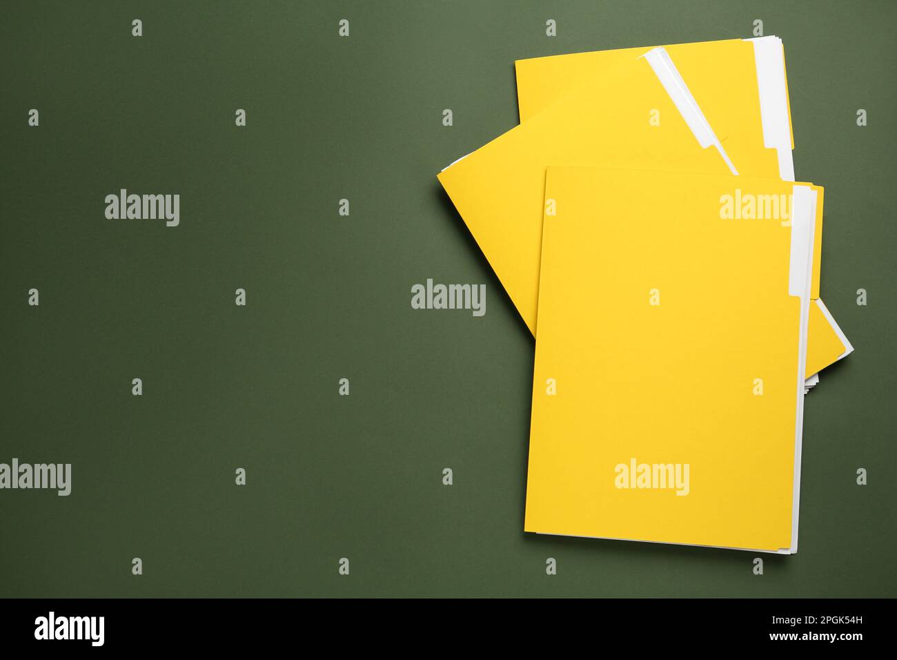 Yellow files with documents on dark green background, top view. Space ...