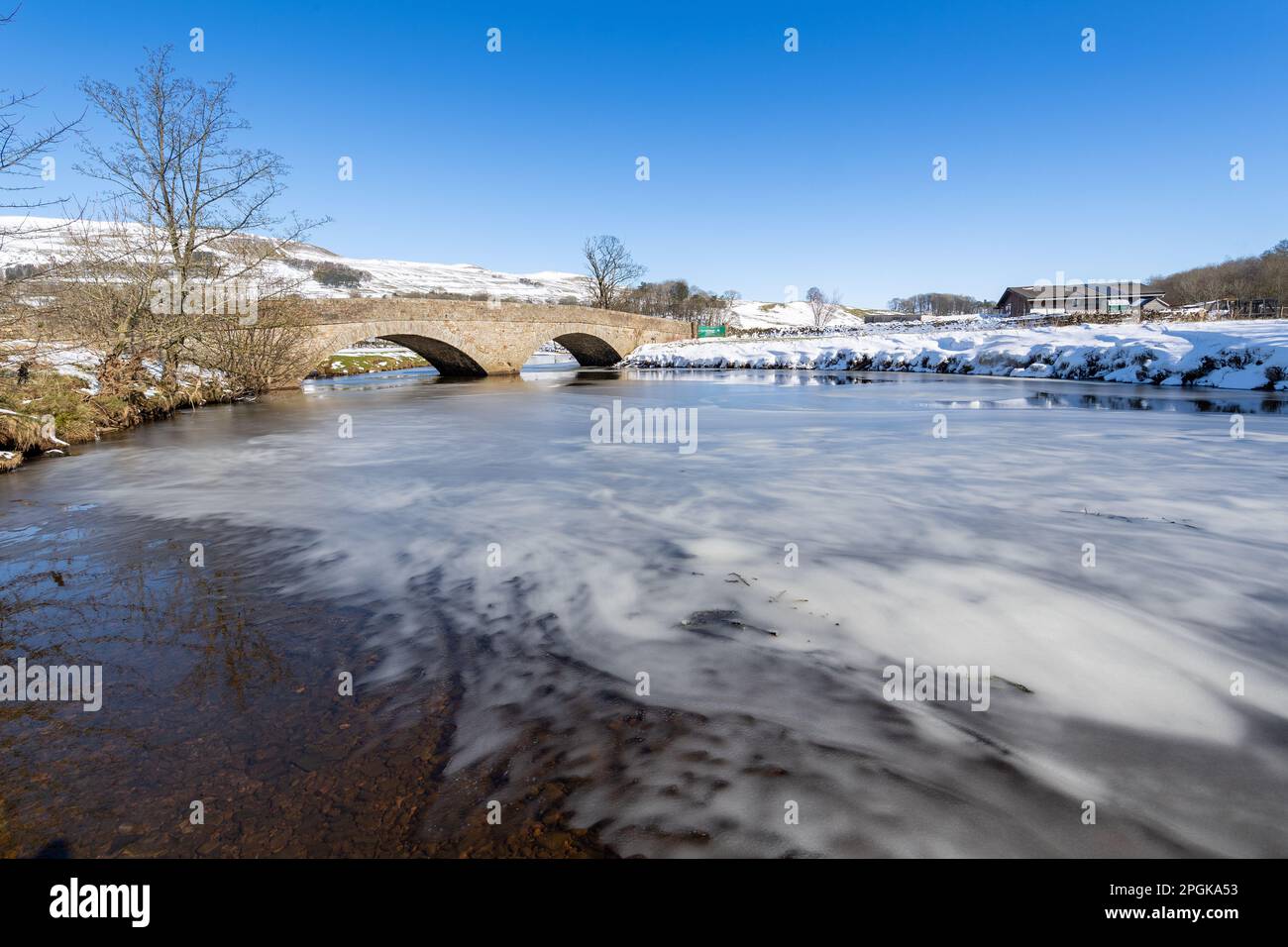 Haylands Bridge on the River Ure near Hawes, with the river part frozen in a cold winter spell. Yorkshire Dales National Park, UK. Stock Photo