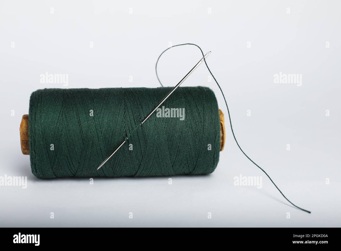 Green sewing thread with needle on white background Stock Photo Alamy
