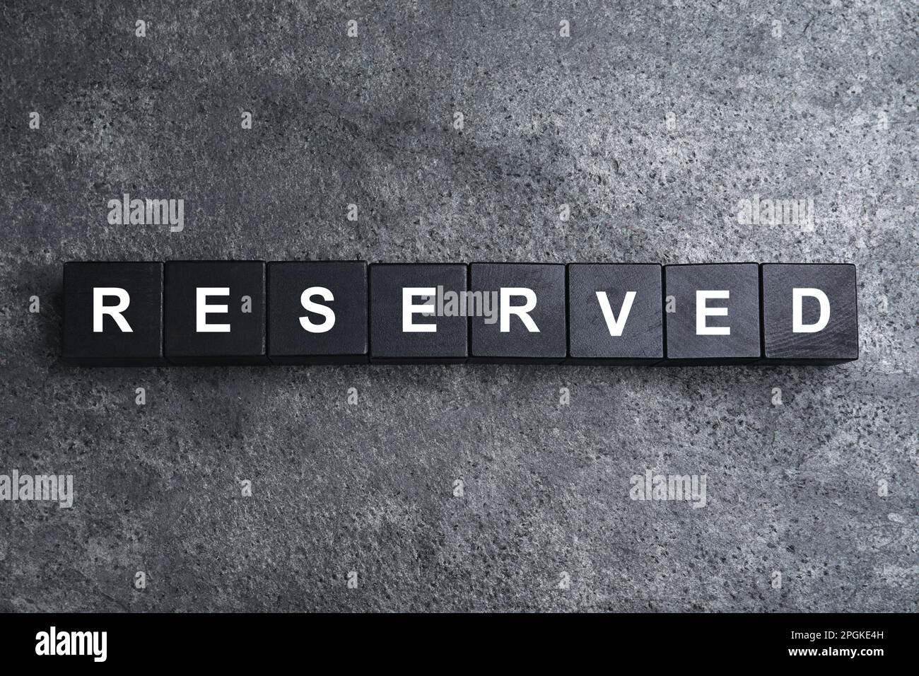 Word RESERVED made with cubes on grey surface, top view. Table setting element Stock Photo