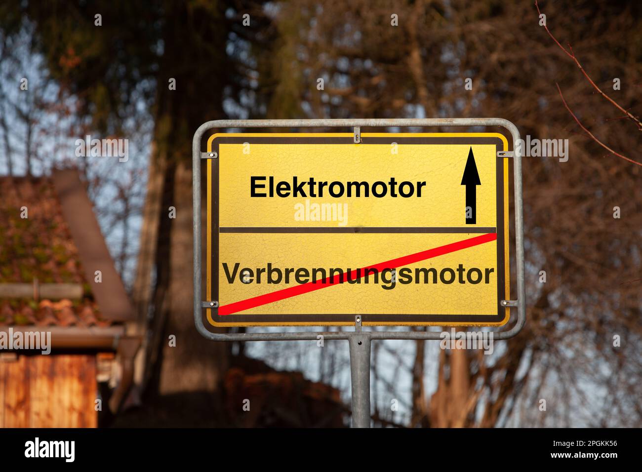 Place sign with internal combustion engine crossed out in red and electric motor with black arrow. Writing in German language. Stock Photo
