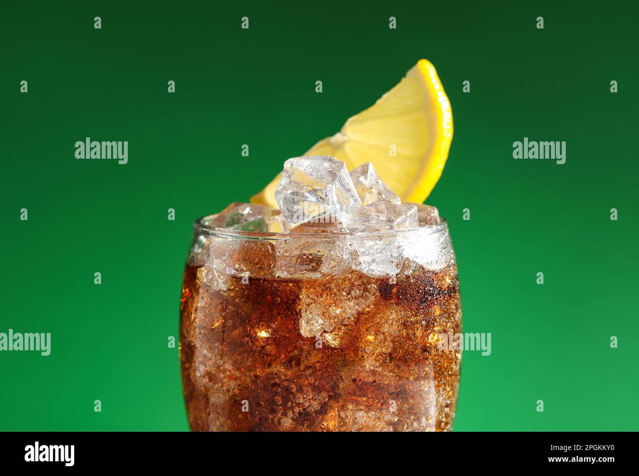 https://c8.alamy.com/comp/2PGKKY0/glass-of-refreshing-soda-drink-with-ice-cubes-and-lemon-on-green-background-closeup-2PGKKY0.jpg