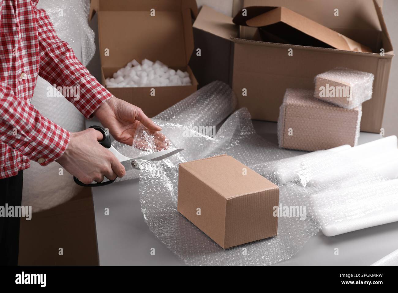 Woman cutting bubble wrap at table in warehouse, closeup Stock Photo Alamy