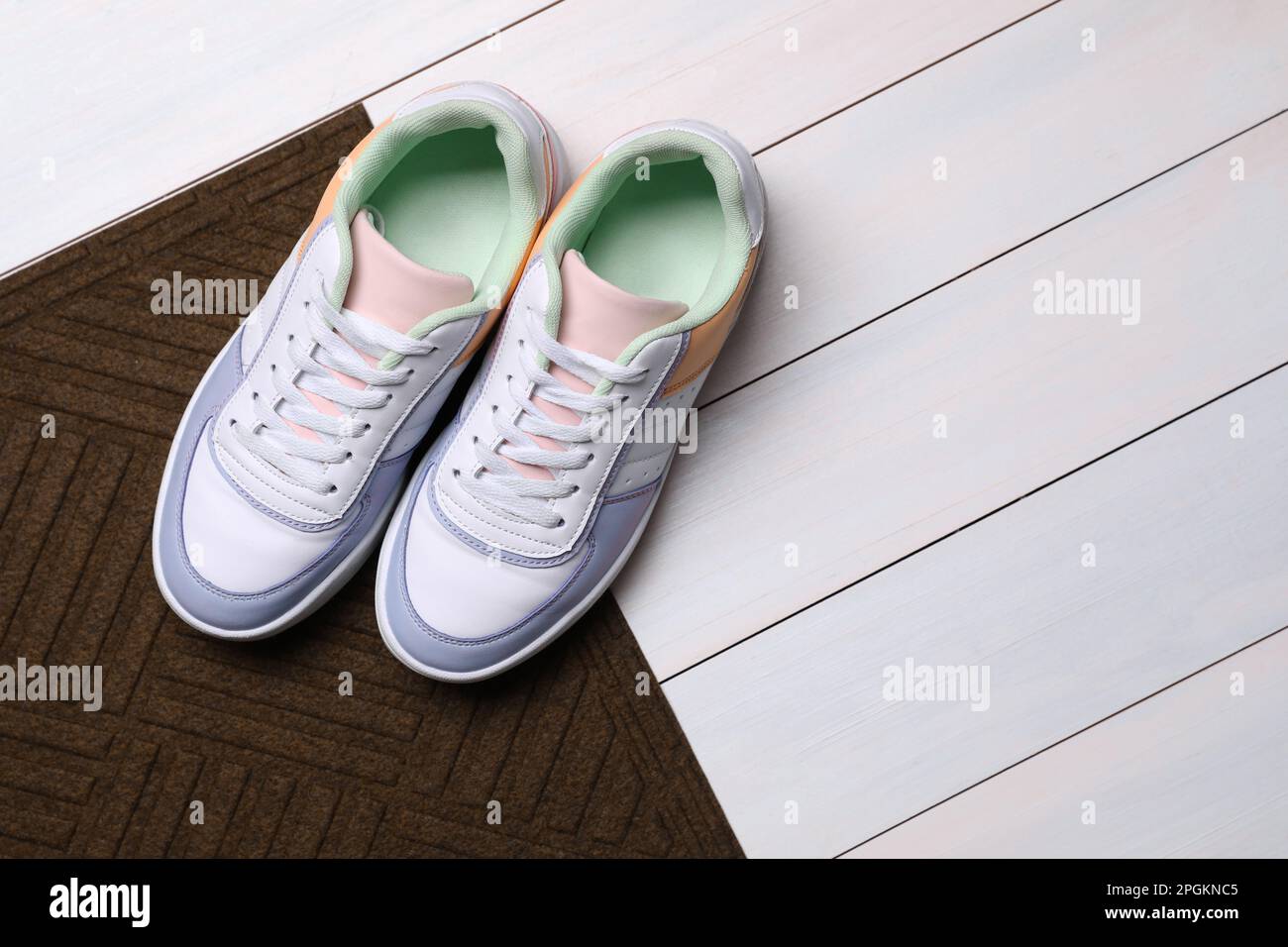 New clean door mat with shoes on white wooden floor, flat lay. Space