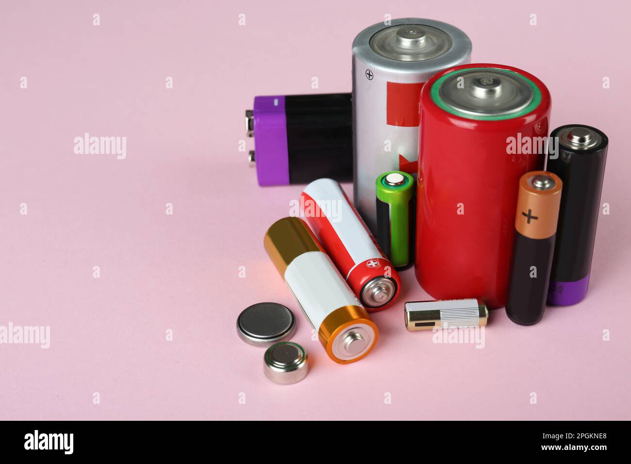 Different types of batteries on pink background, space for text Stock