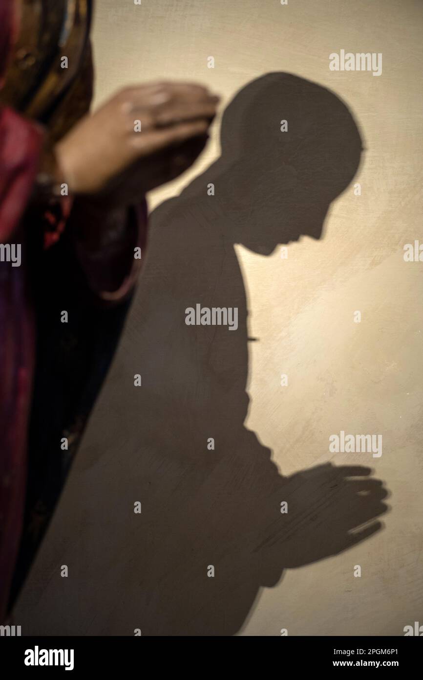 Shadow of a statue shown in prayer in the Bargello museum in Florence