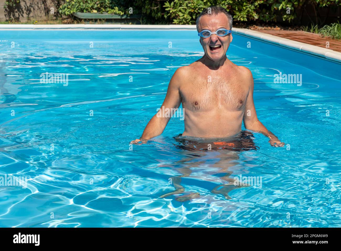 Middle aged white man wearing swimming goggles, submerged in water with satisfied expression Stock Photo