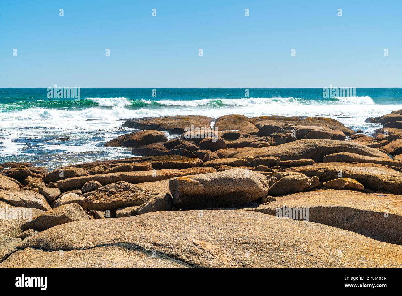 Beautiful serene sea shore in with big red rocks on a sunny day with blue sky. Stock Photo