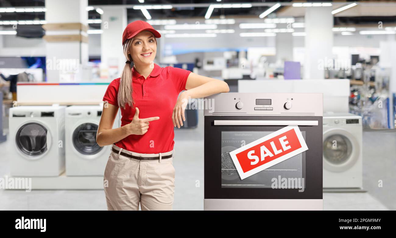 Saleswoman pointing at an electrcal oven inside an electrical appliance shop Stock Photo