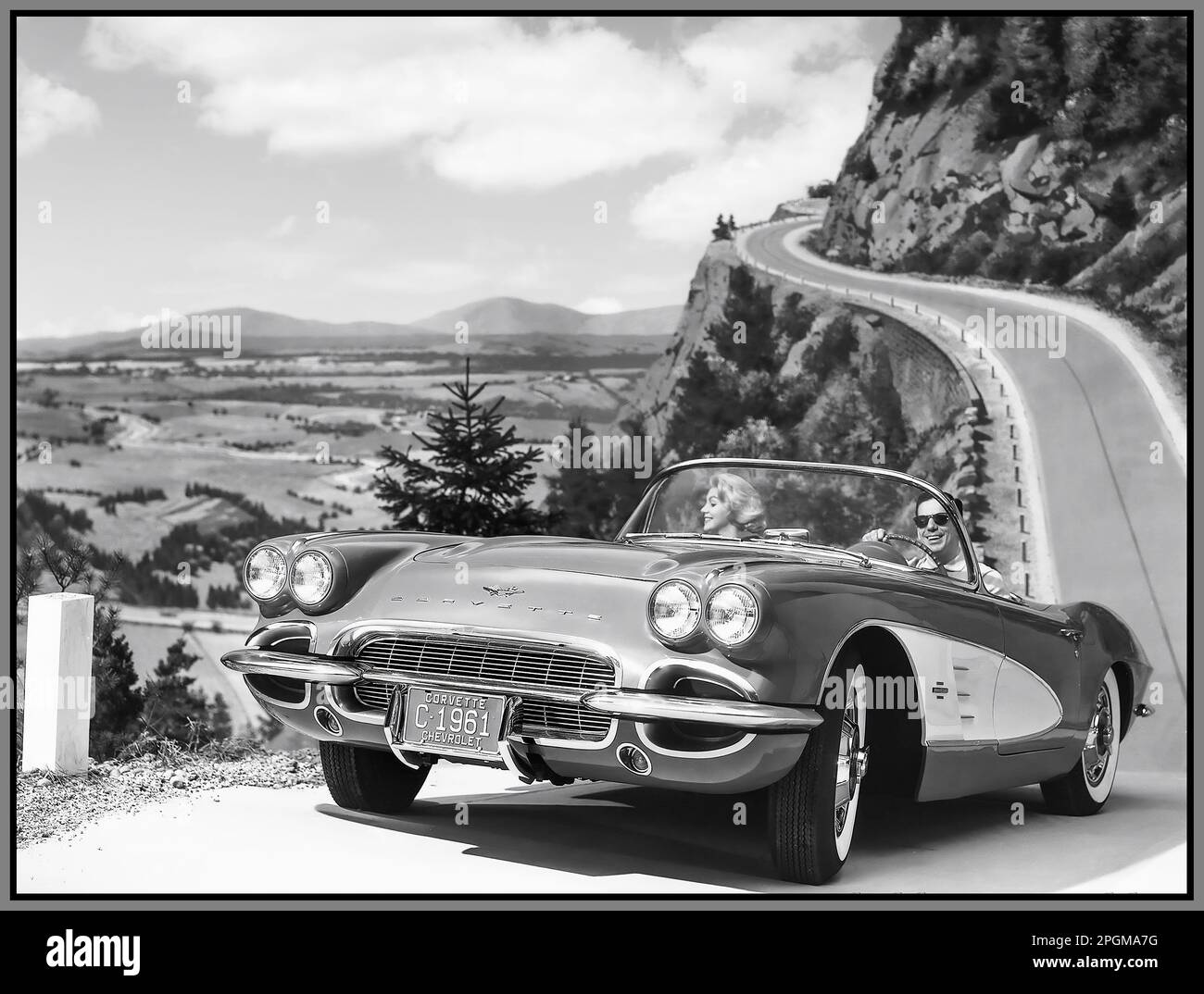 1960s Chevrolet Corvette 1961 open top 2 seater sports car motorcar product image photograph with model in outdoor winding mountainous road lifestyle fashion situation Stock Photo