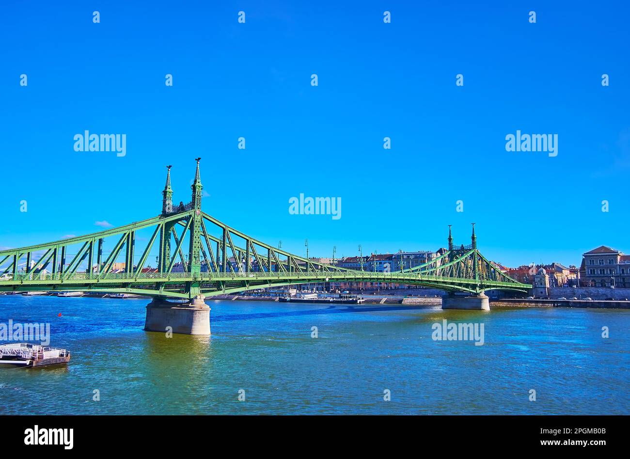 The picturesque Liberty Bridge, stretching across Danube River with a view on historic building of Corvinus University on the opposite river's bank, B Stock Photo