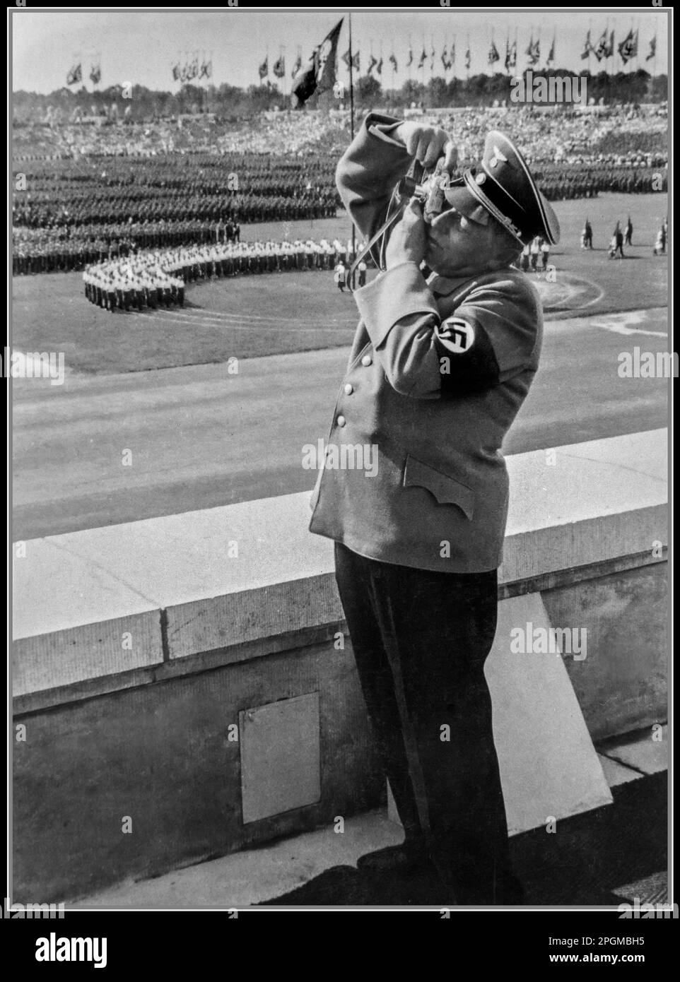 NUREMBERG Nazi official wearing a swastika armband photographs a huge Nazi Party Nuremberg Rally in the 1930s, using a German Leica 35mm film camera Nuremberg Nazi Germany (from the Eva Braun Photo Albums) Stock Photo