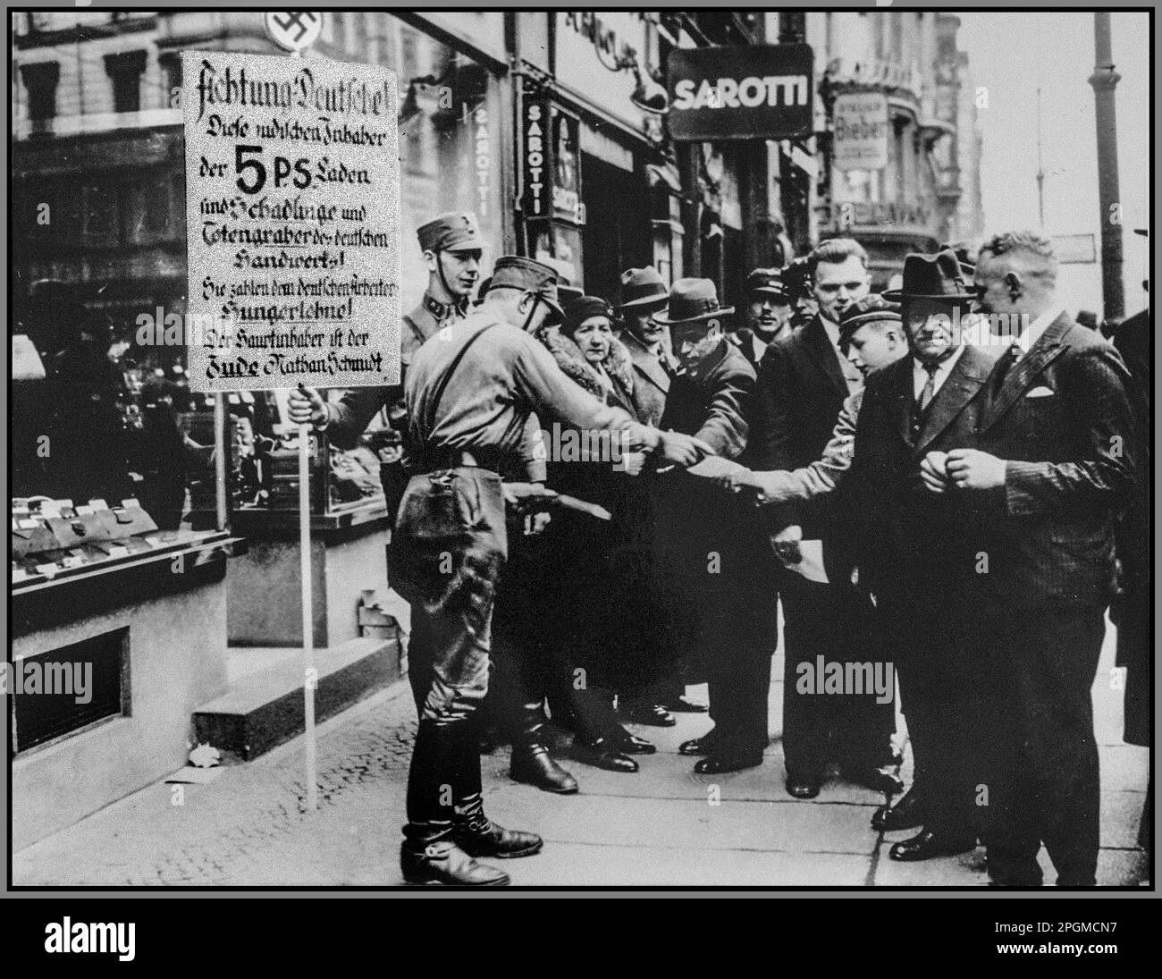 Nazi Germany 1930s Anti semitism anti Jewish racist SA pickets distribute boycott pamphlets to German pedestrians. The sign held by one of them reads: 'Attention Germans. These Jewish owners of [five and dime] stores are the parasites and gravediggers of German craftsmen. They pay starvation wages to German workers. The shop owner is the Jew, Nathan Schmidt.' Antisemitism in Nazi Germany Stock Photo