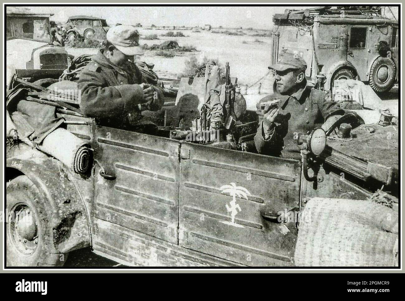 Afrika Corps WW2 North Africa 1940s Nazi Germany 21st Panzer Division under  Desert Fox Field Marshall Erwin Rommel, Wehrmacht Army Soldiers eating rations in their Kubelwagon. 'DAK' Nazi Swastika stencil on the door. World War II Second World War Stock Photo