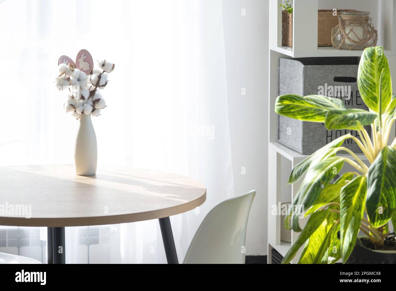 A bouquet of cotton twigs in a vase on a round table with an Easter