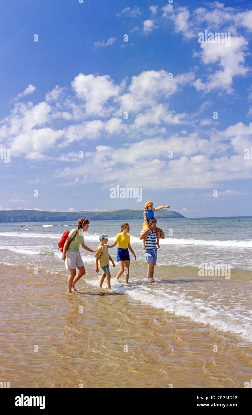 Holiday Family Devon Beach UK. Family of five enjoying a stroll along the beach in Devon UK. Perfect summers day staycation, with warm sunshine, calm water and surf at the waters edge Woolacombe Devon  UK Stock Photo