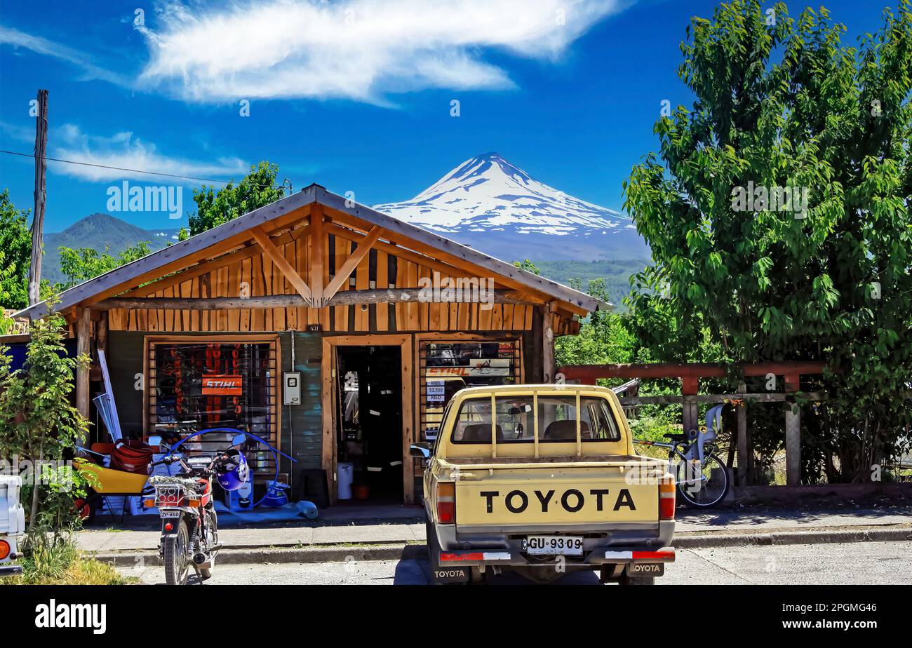 Conguillio NP, Chile: December 23. 2011: Traditional chilean andes mountains wooden store building, Toyota truck parking, volcano llaima peak Stock Photo