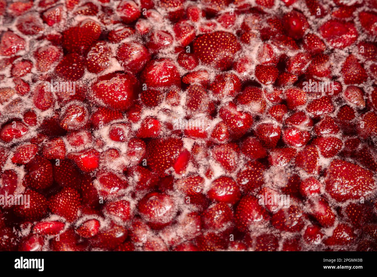 Process of making homemade raspberry jam. Red sweet syrup boiling on the stove closeup. Strawberry jam looks very appetizing. Boiling homemade strawberry jam. Make a strawberry jam. Stock Photo