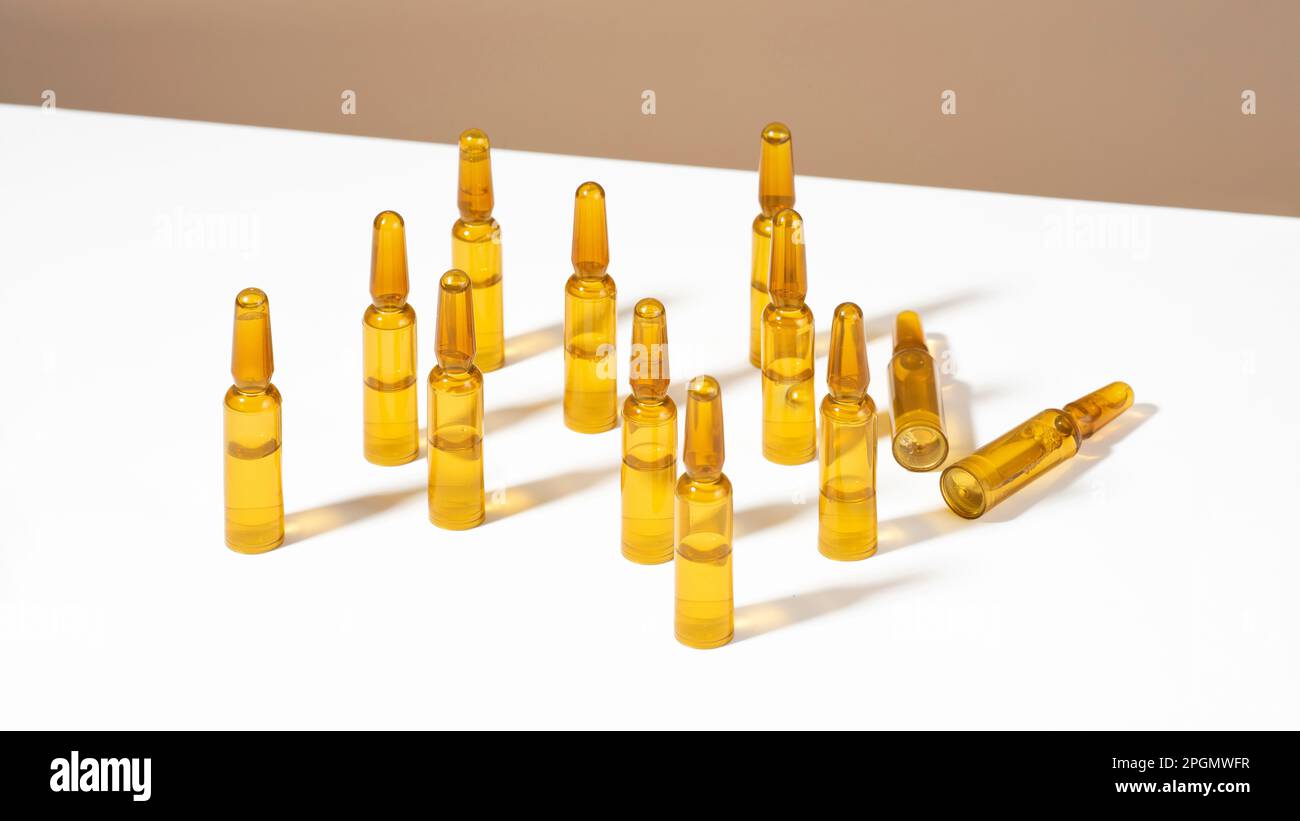 Cosmetic glass ampoules with serum on white and brown background with