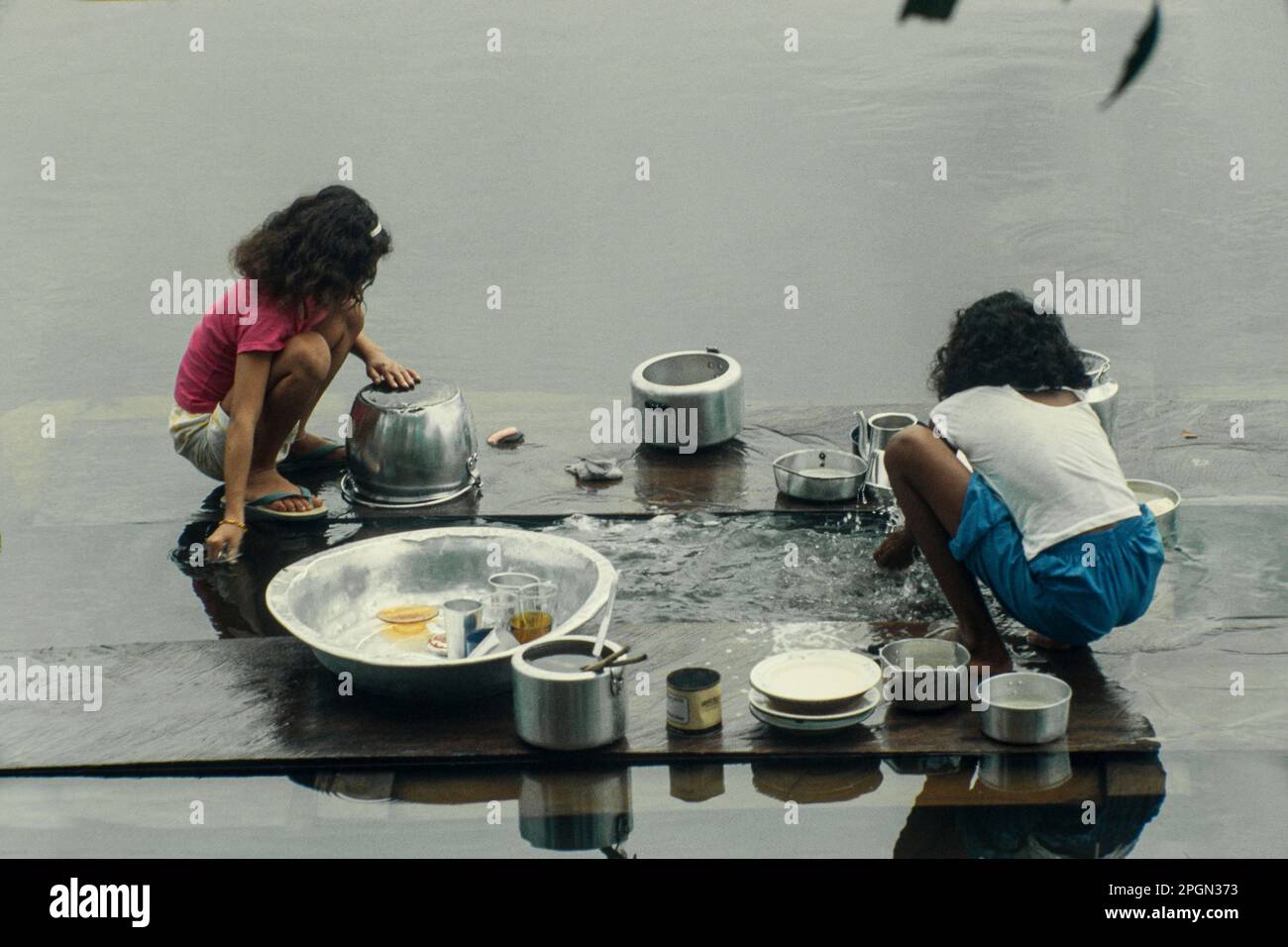 Daily life at Brazilian Amazon village, children wash the dishes at nearby river. Stock Photo