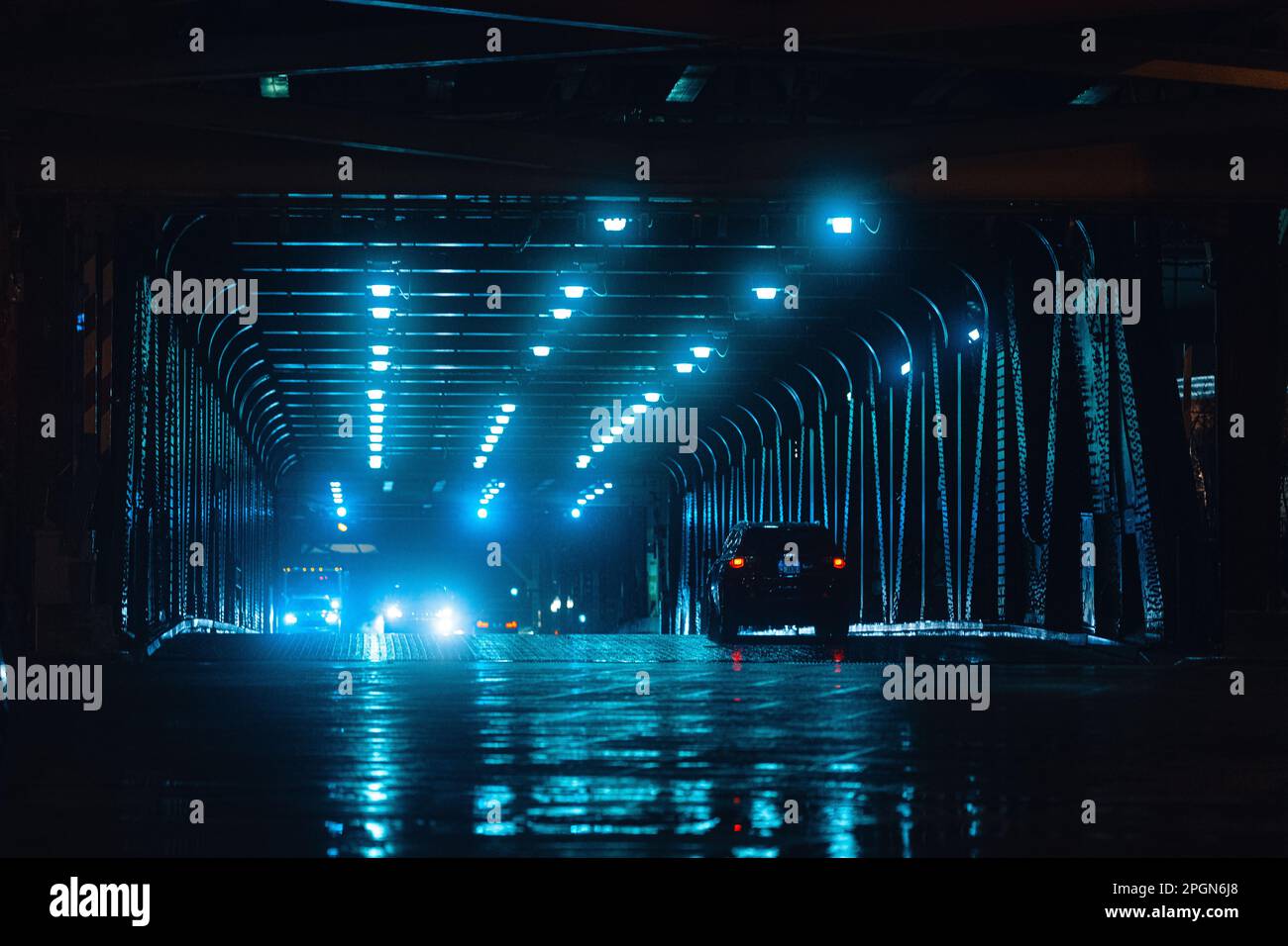 A low-lit night-time scene on a bridge, illuminated by the city lights in the background Stock Photo