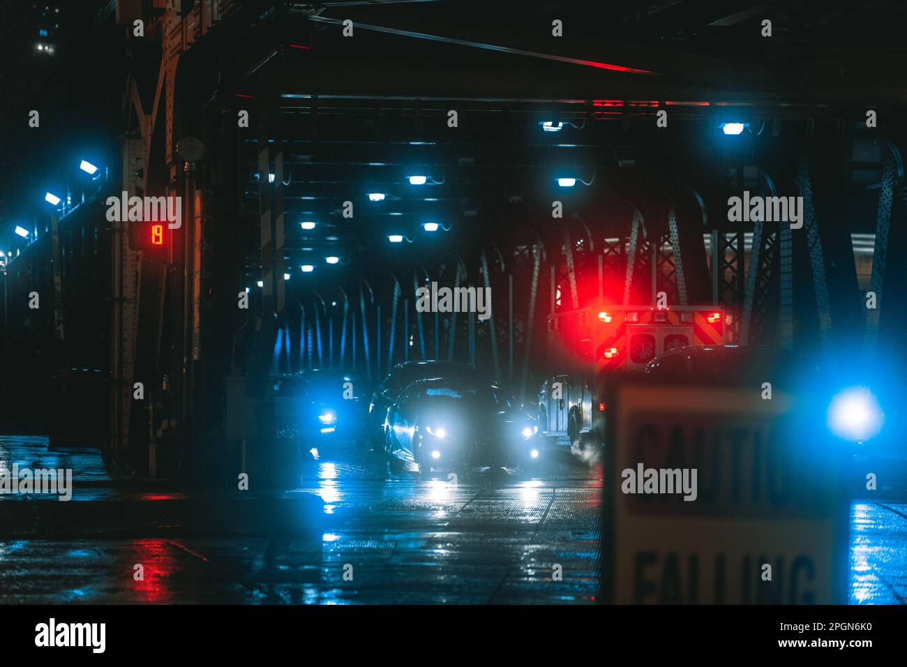 A low-lit night-time scene on a bridge, illuminated by the city lights in the background Stock Photo