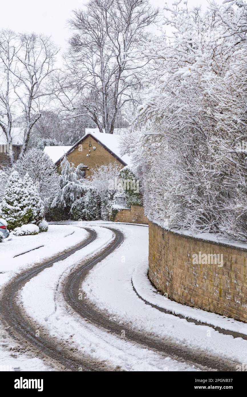 A snow covered road in Baildon, Yorkshire. Cars have driven over the snow leaving tyre marks. Stock Photo
