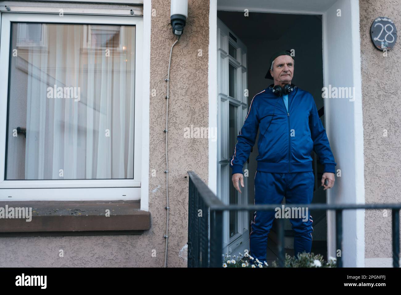 Staning Sportive senior man in tracksuit staning in house entrance Stock Photo ...