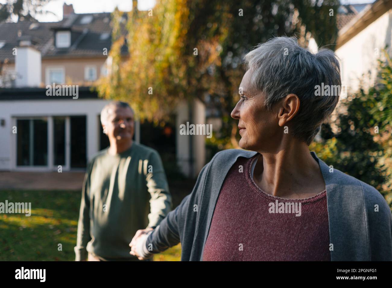 Affectionate senior couple holding hands in garden Stock Photo
