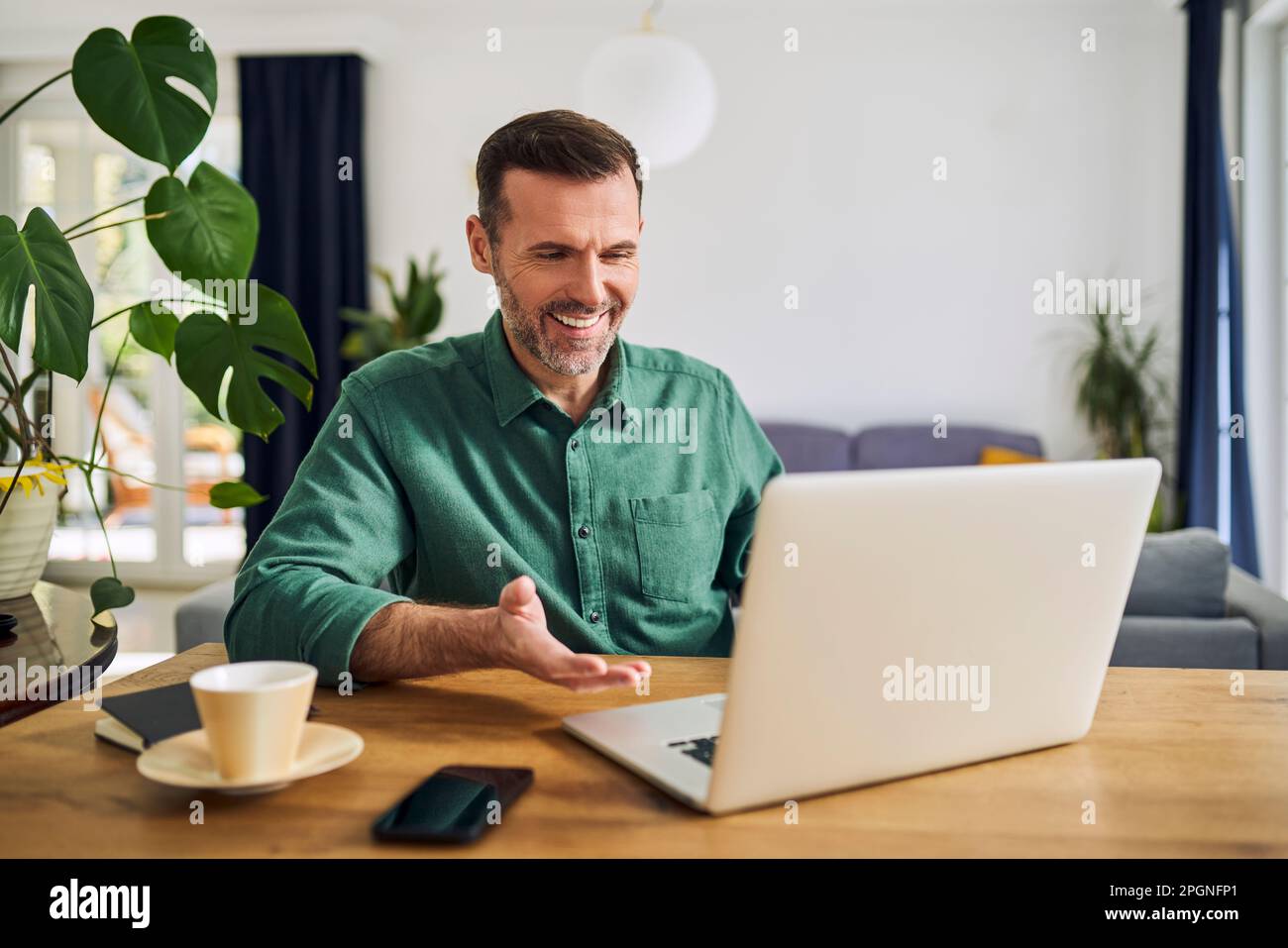 Man having video call sitting at desk using laptop Stock Photo