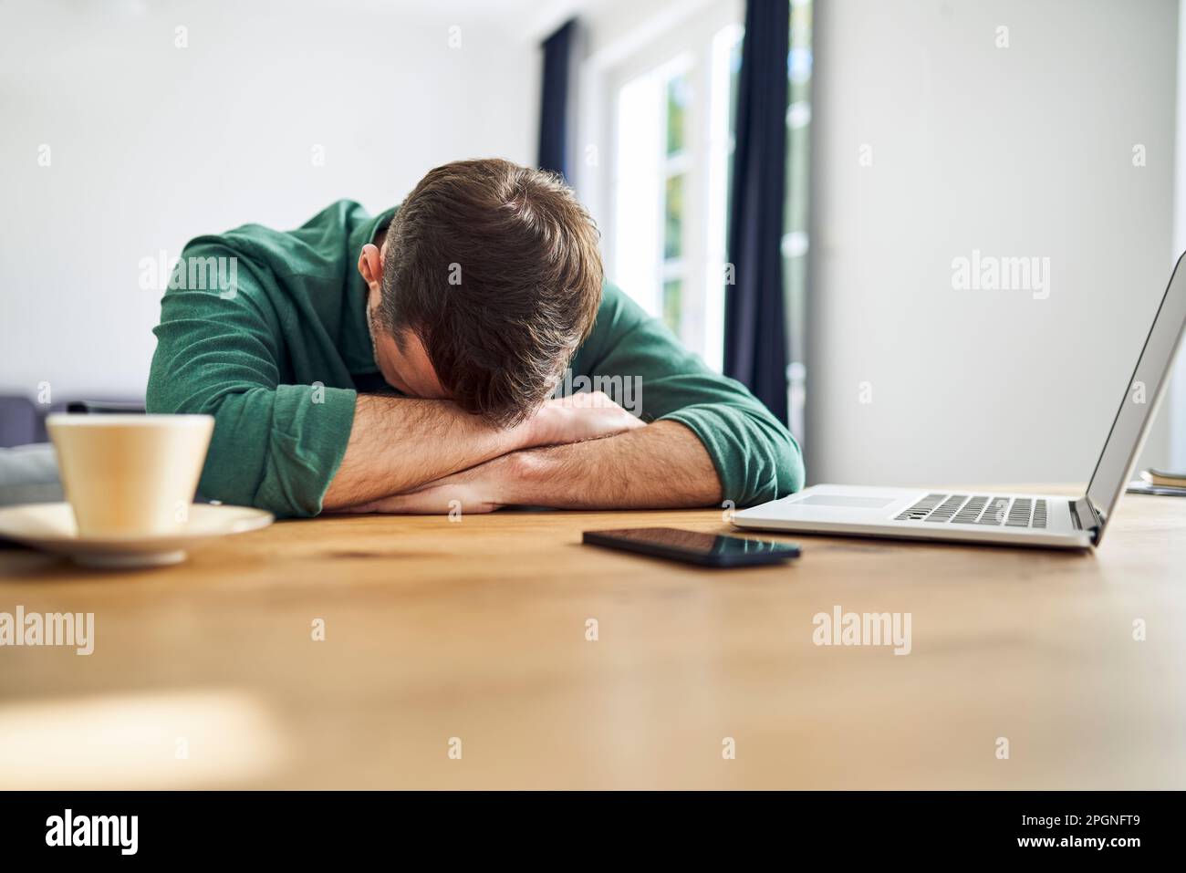 Overworked man sleeping on arms at desk Stock Photo Alamy