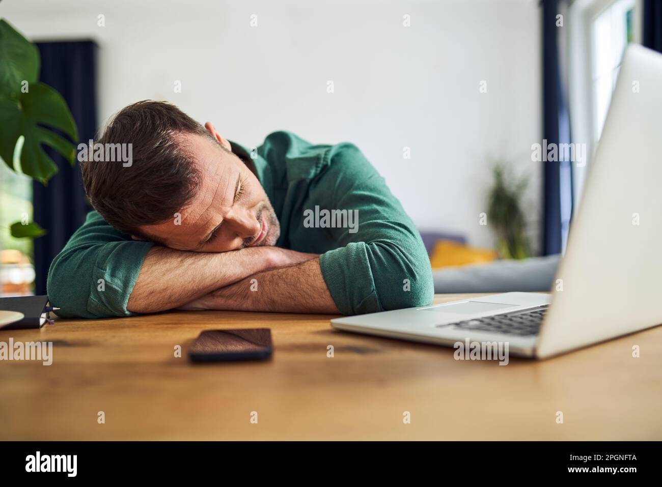 Overworked man sleeping on arms at desk Stock Photo Alamy