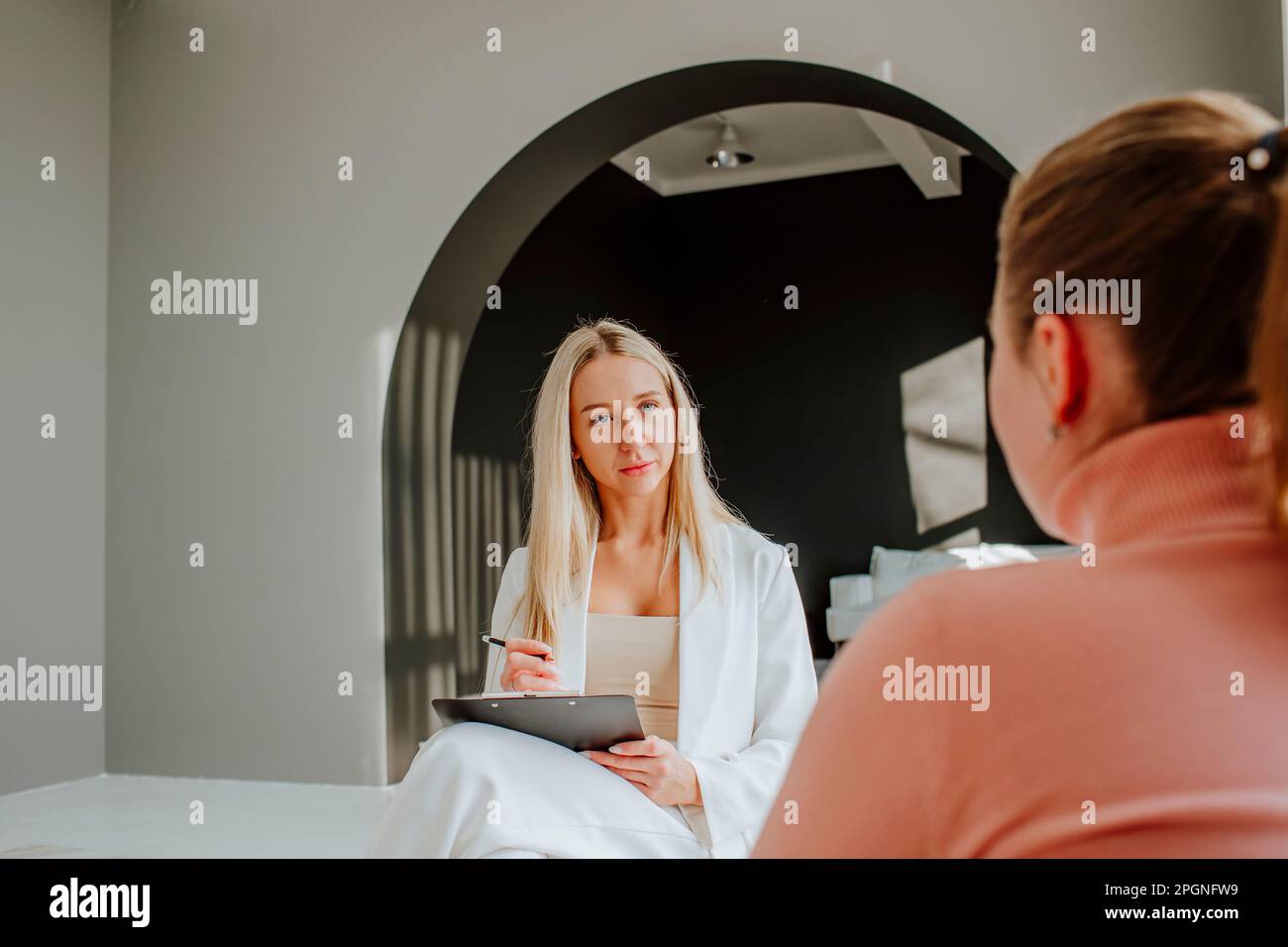 Psychologist taking notes in counseling session at clinic Stock Photo