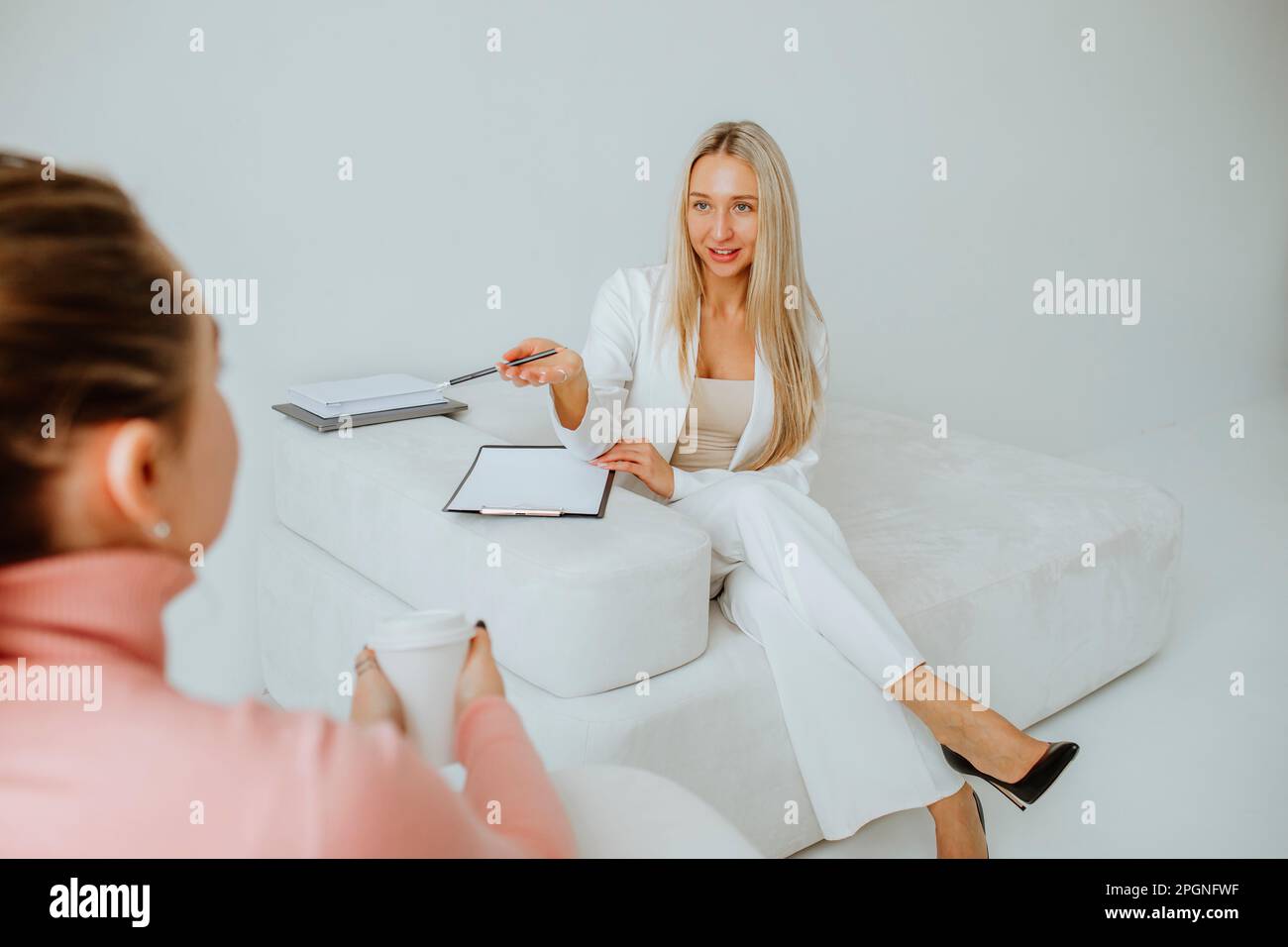 Young psychologist with clipboard advising patient in clinic Stock Photo