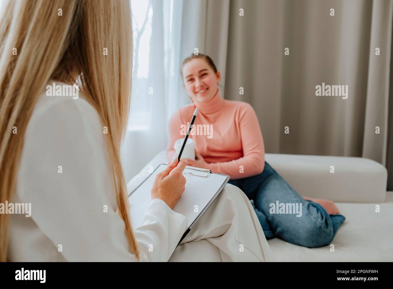 Smiling patient discussing with psychologist in clinic Stock Photo