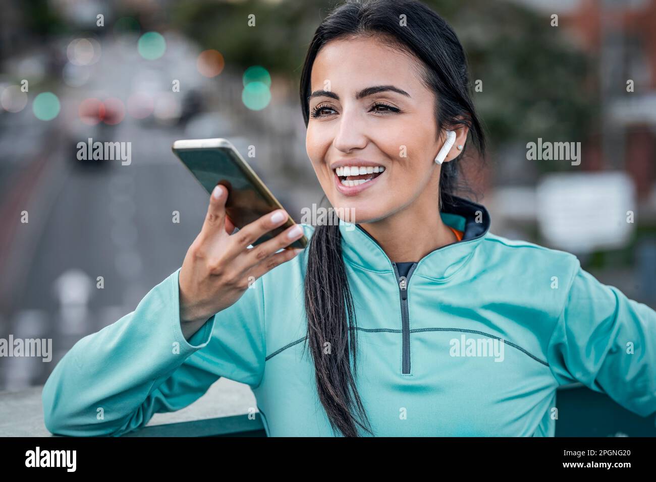 Happy woman wearing wireless in-ear headphones and talking on speaker ...