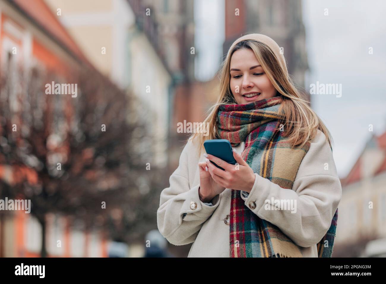 Smiling young woman using mobile phone Stock Photo