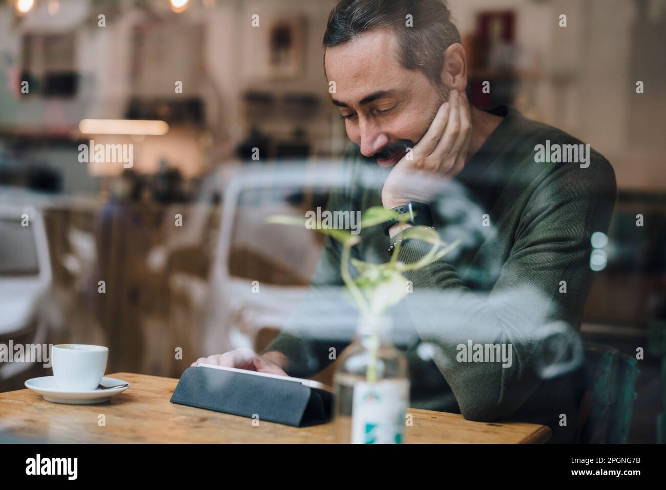 Smiling man watching videos on tablet PC in cafe Stock Photo