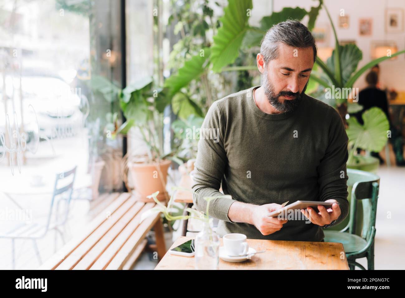 Mature man using tablet PC sitting at table in cafe Stock Photo