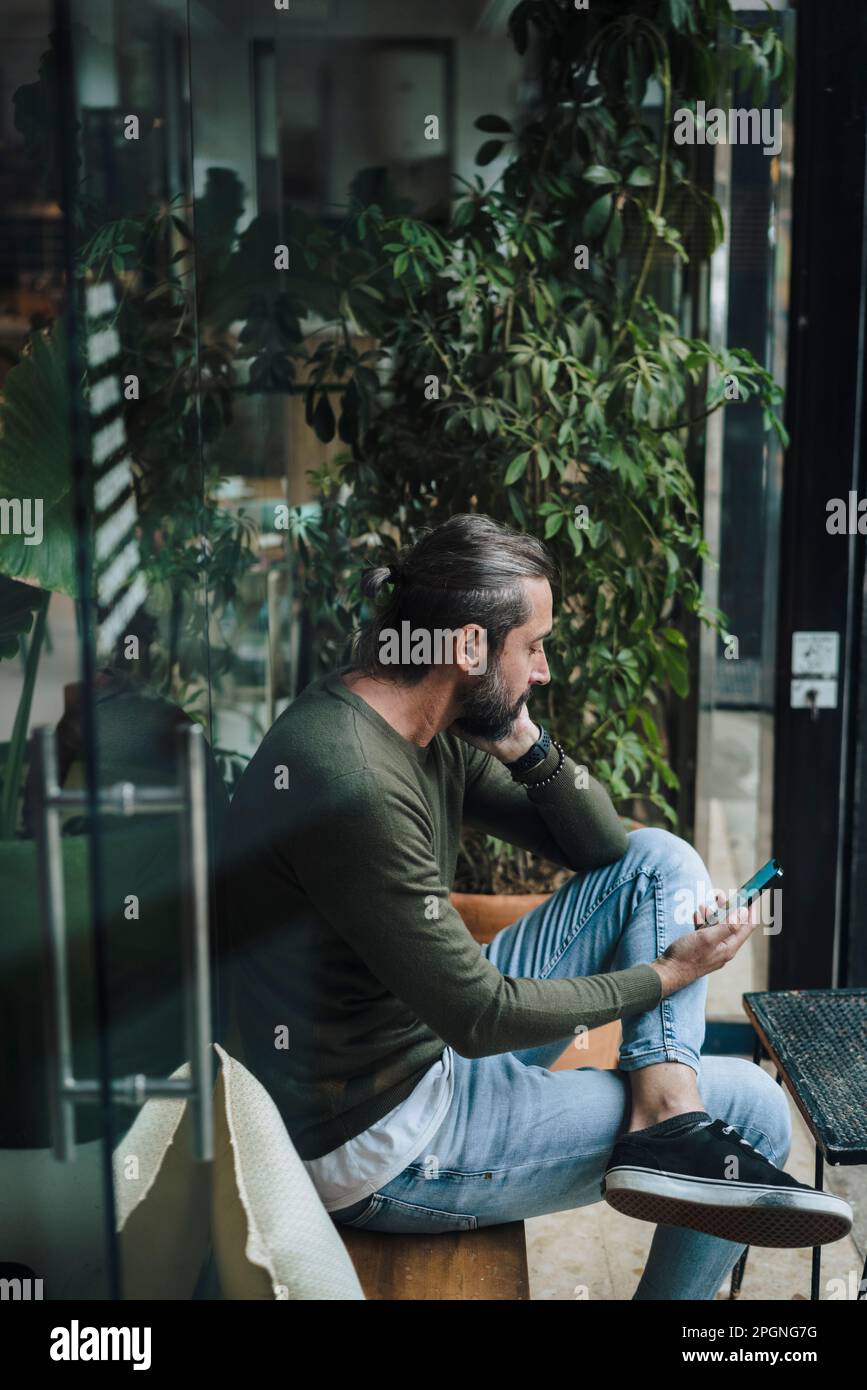 Mature man using smart phone in cafe Stock Photo