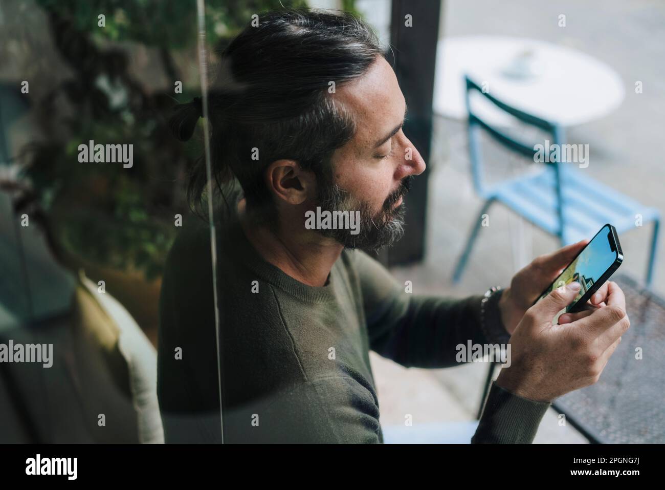 Man using smart phone sitting in cafe Stock Photo