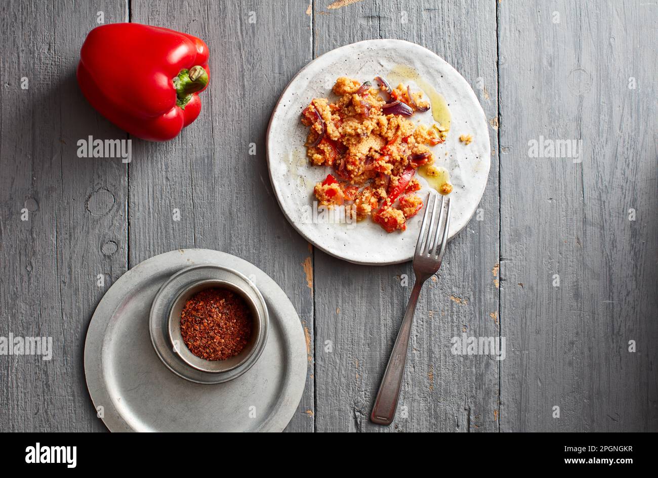 Raw bell pepper, chili powder and plate of ready-to-eat couscous Stock Photo