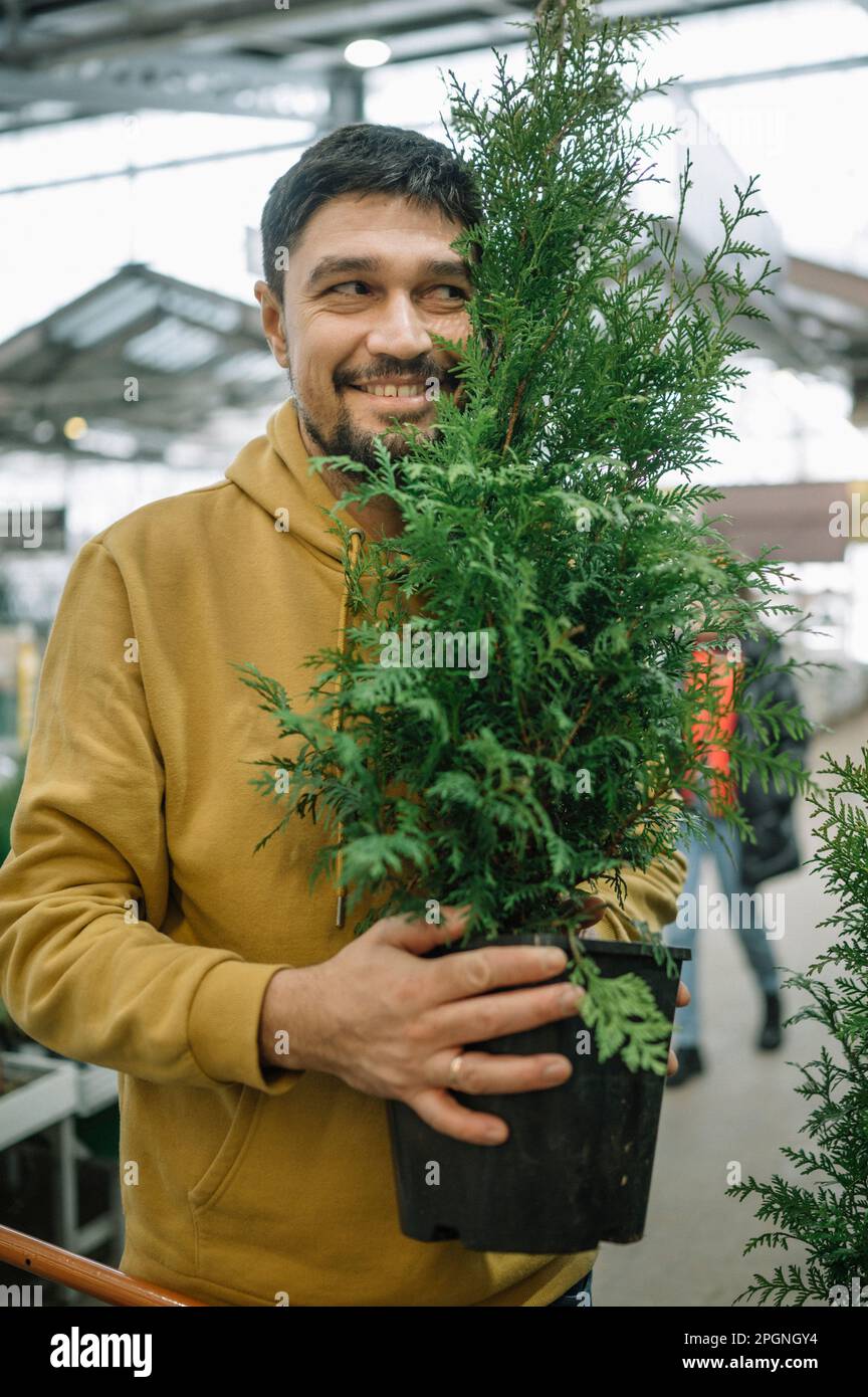 Happy man holding potted plant at store Stock Photo - Alamy