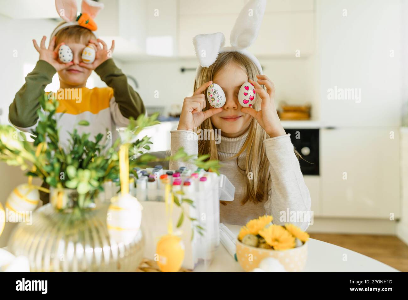 Happy boy and girl holding Easter eggs over eyes Stock Photo