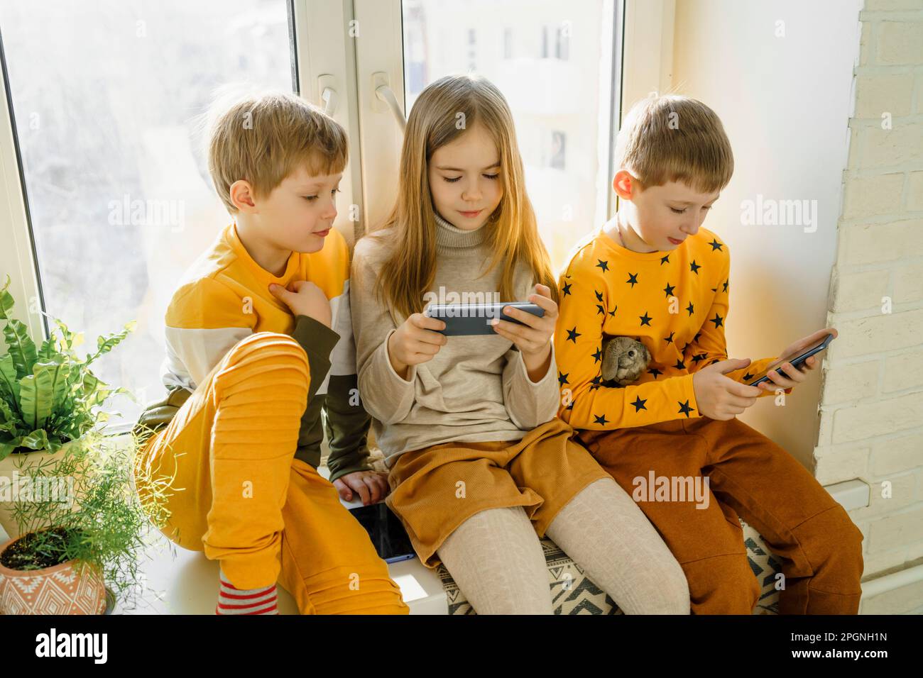 Happy boy with siblings using smart phone at home Stock Photo
