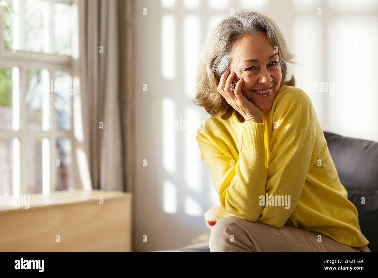 Mature woman sitting on sofa hi-res stock photography and images - Alamy
