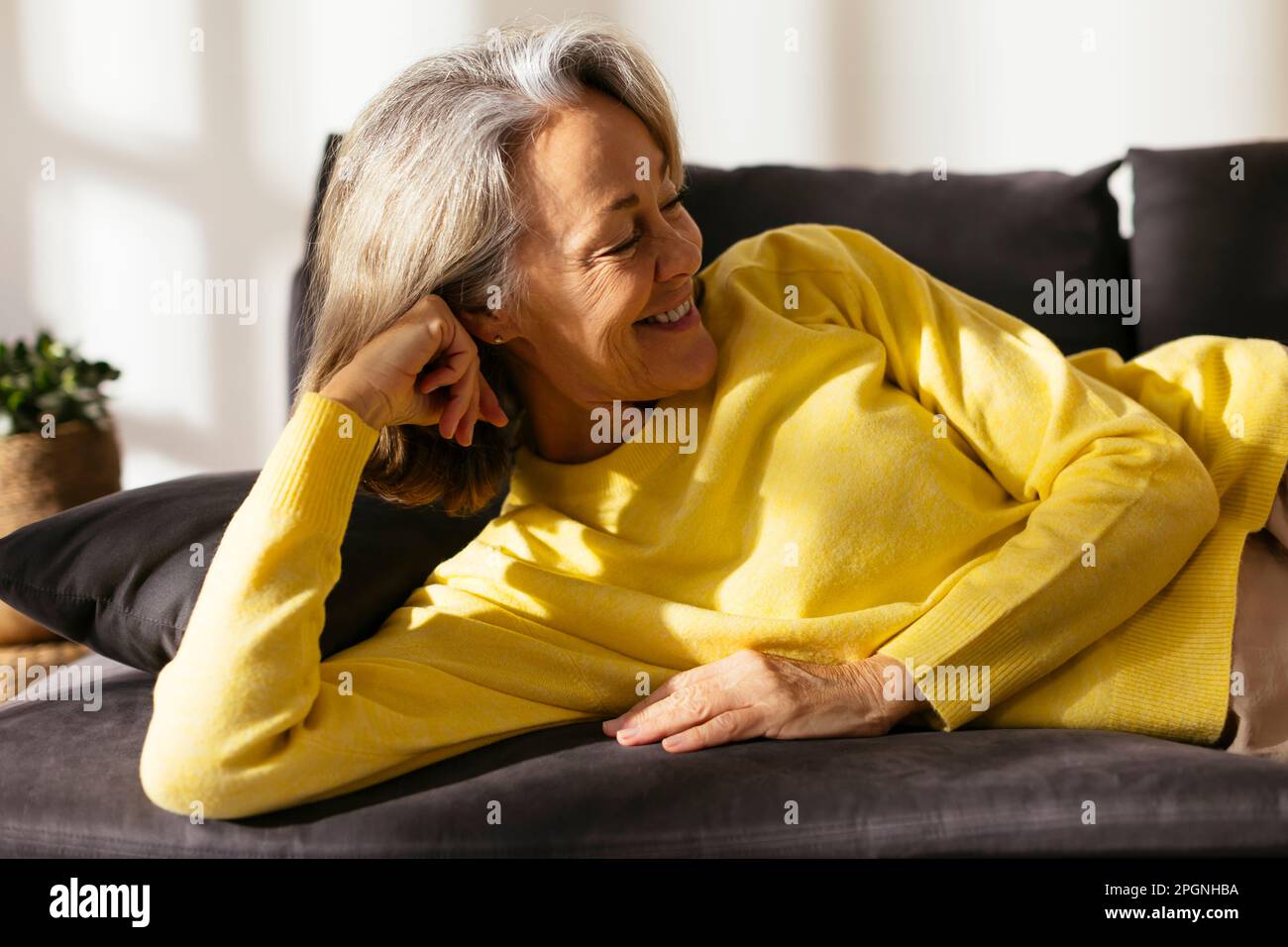 Happy mature woman relaxing on sofa at home Stock Photo - Alamy