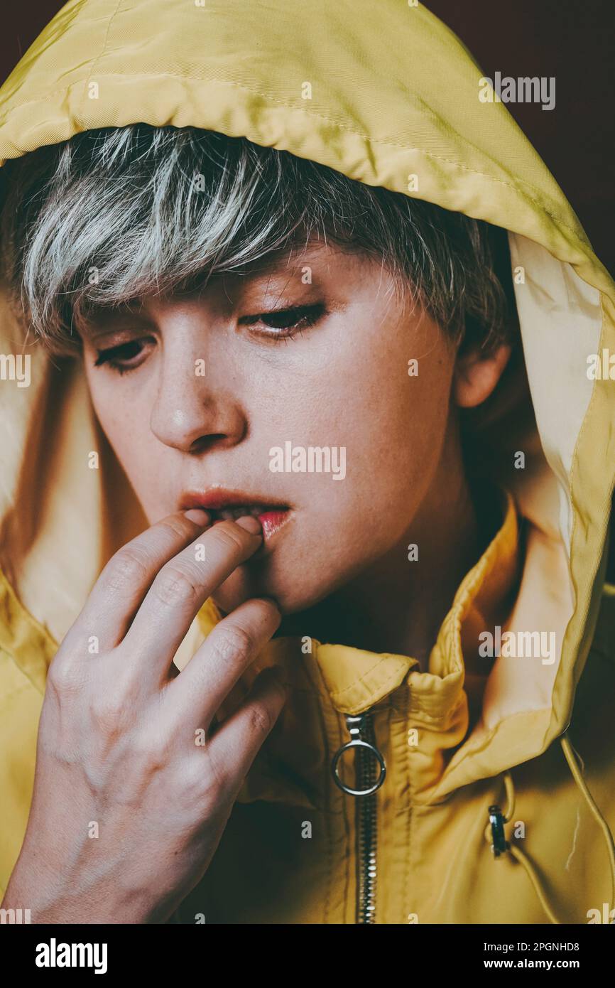 Thoughtful woman wearing yellow hooded jacket Stock Photo